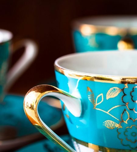 About Close-up of elegant blue porcelain teacups adorned with gold floral patterns.